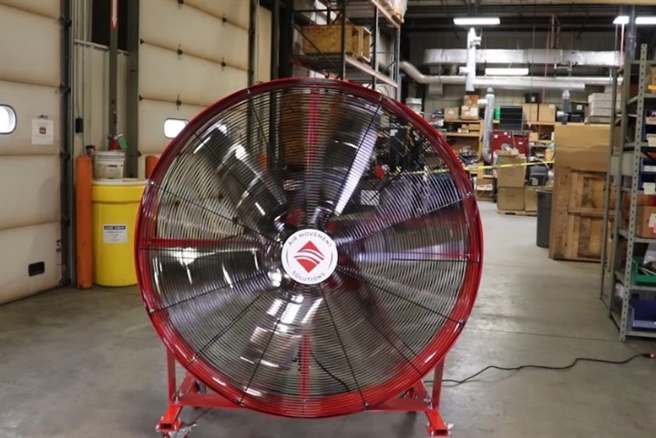 A red AirMobile fan standing near large doors of a workshop.