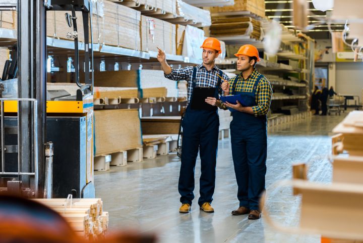 Workers in hard hats at a manufacturing facility cooled by industrial factory fans