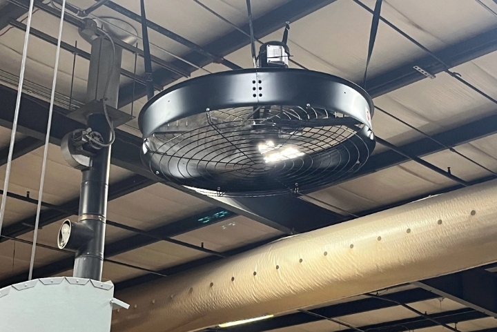 A black AirFocus fan hanging from the ceiling of a warehouse.