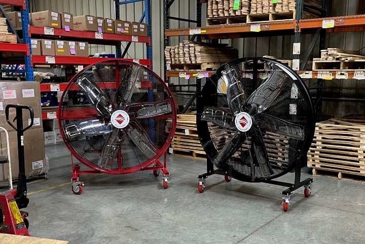 A black and red AirMobile directional fan standing side by side in a warehouse.